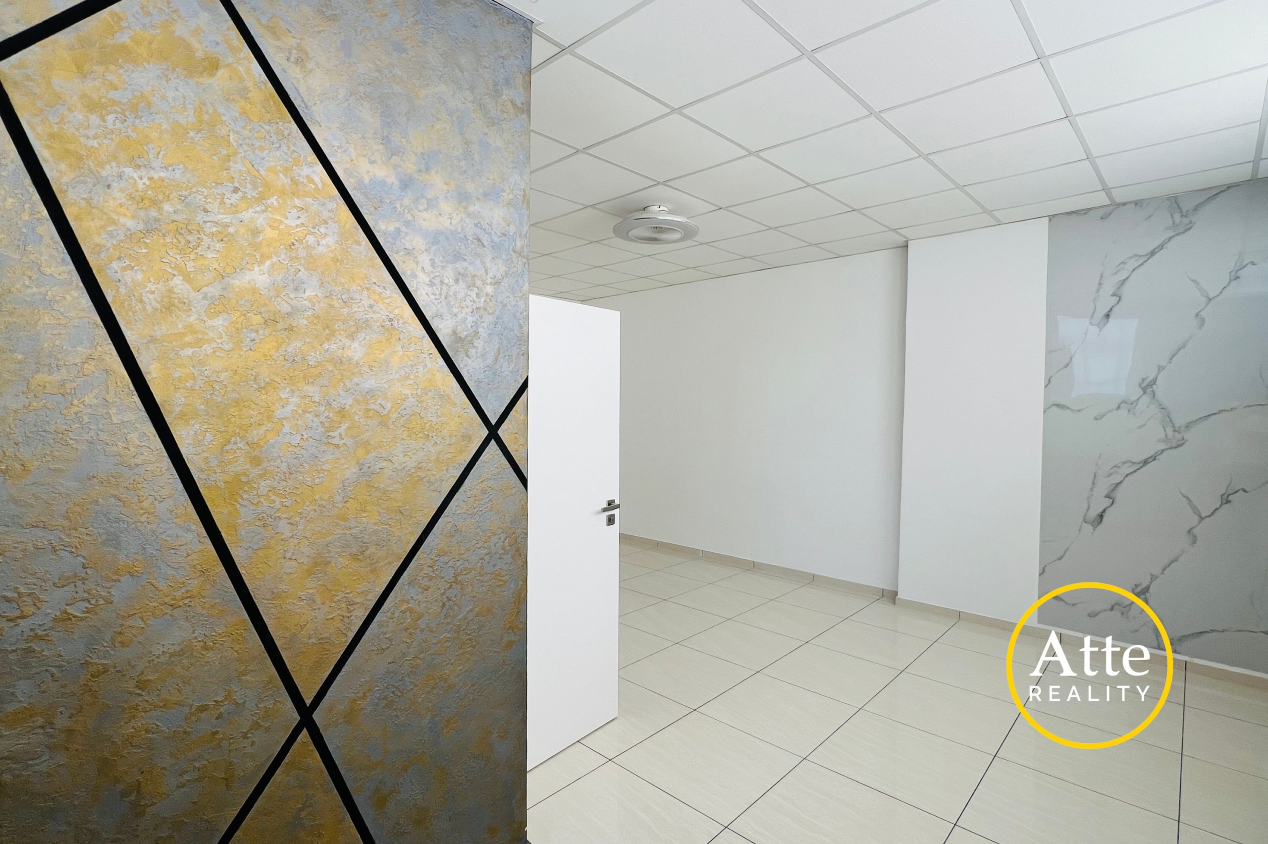 Interior showroom scene featuring a large textured wall panel in gold and blue with black diagonal lines, a white door, and tiled floor.
