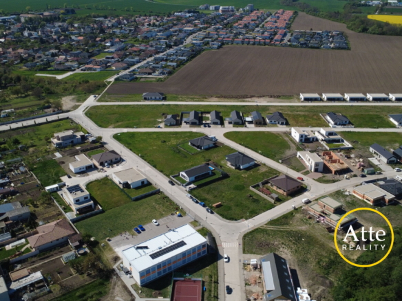 Aerial view of a suburban development with rows of new houses, roads, and surrounding fields.